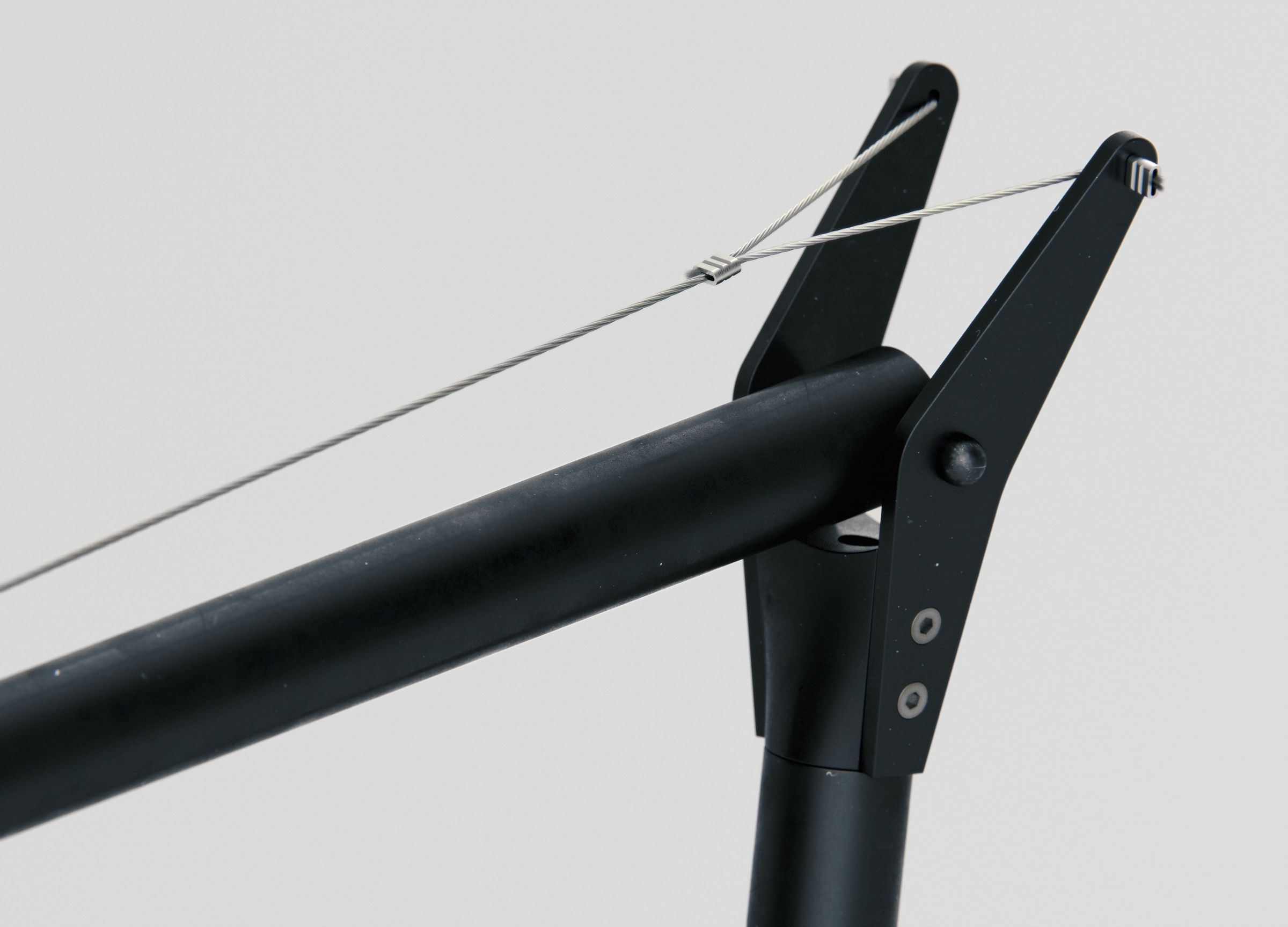 Close-up of the top pivot joint where the tensioning cables cross, with visible bolts.