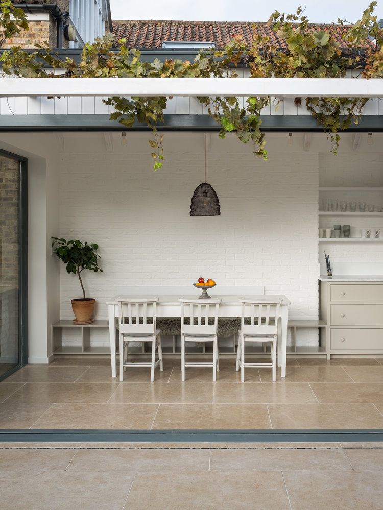 View through the glazed kitchen extension roof toward a dining table set against a white-painted brick wall.