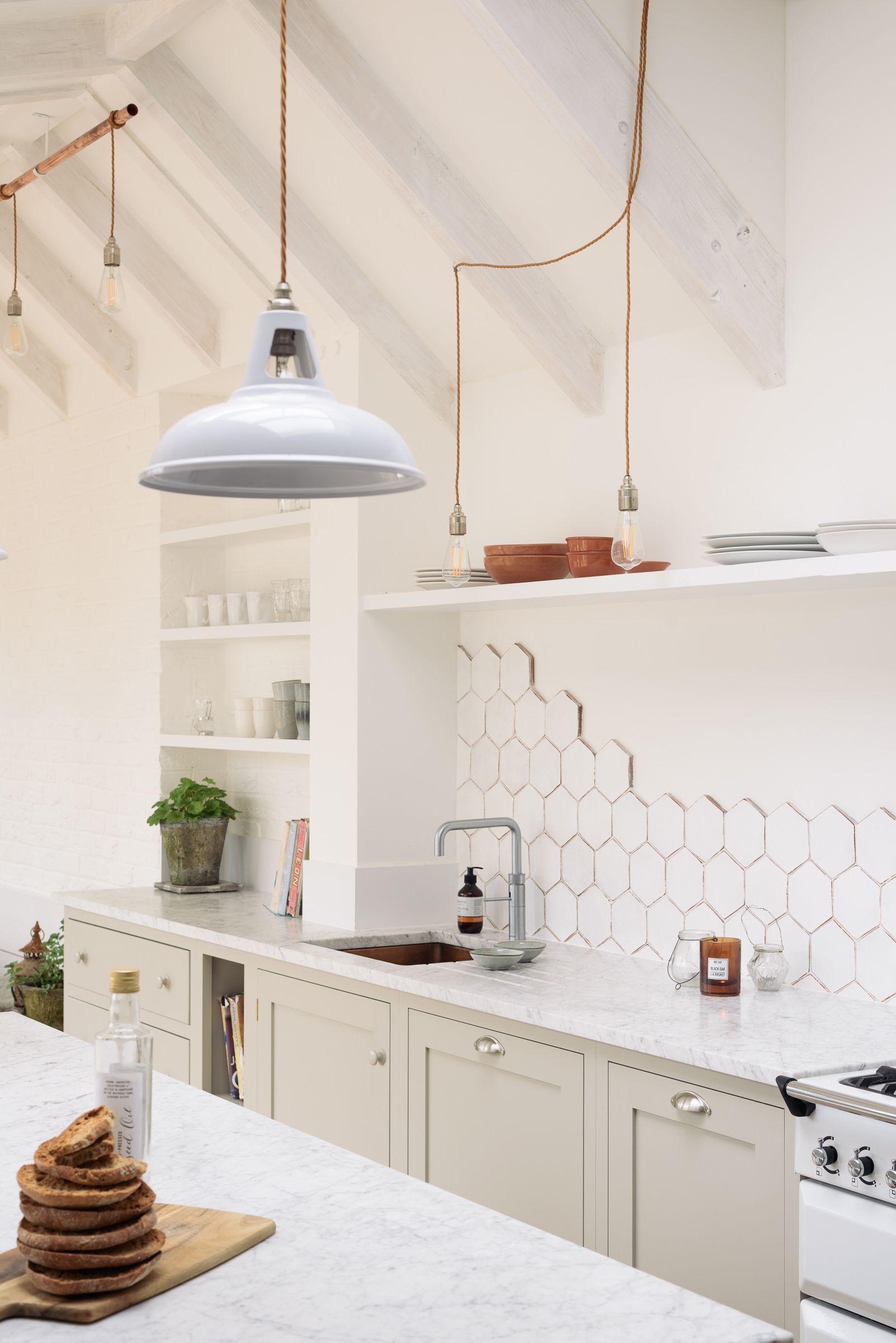 Closer view of pendant lights hanging over the hexagon-tiled splashback and open shelves, with a stack of pancakes on the counter.
